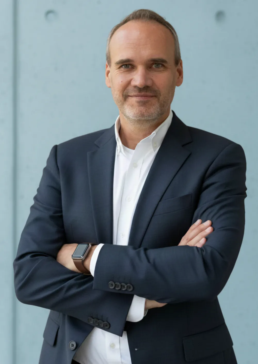 Björn Radde, Gründer von Ditengy, im dunkelblauen Sakko vor einer hellblauen Betonwand